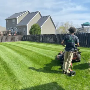 employee on lawn mower cutting grass
